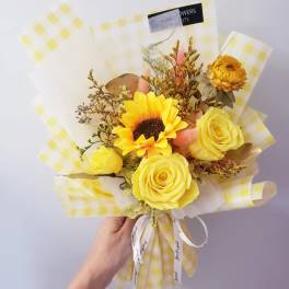 Yellow rose and sunflower bouquet wrapped in checkered paper