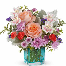 Bouquet of peach roses, purple blooms, and white alstroemeria in a blue vase
