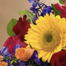 Mixed bouquet with a large yellow sunflower and red roses