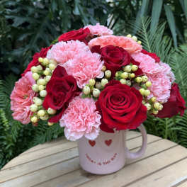 Pink and red flower bouquet in a mug with heart decorations