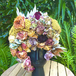 Large bouquet of dried roses and hydrangeas in a black vase