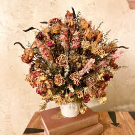 Dried rose bouquet in a white vase on stacked books