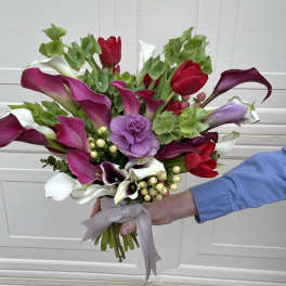 Handheld bouquet of calla lilies and tulips in pink, white, and red