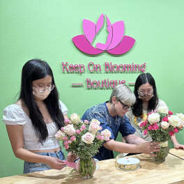 People arranging pink and white rose bouquets in glass vases