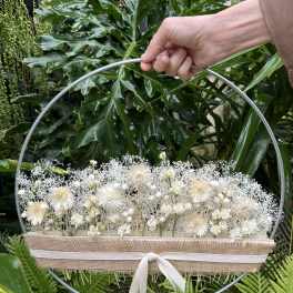 White floral arrangement in a round metal hoop with a ribbon-tied burlap wrap