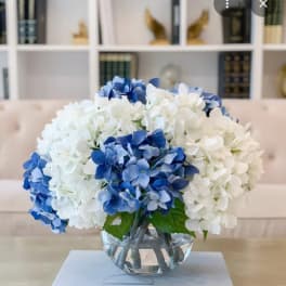 Blue and white hydrangeas arranged in a clear glass bowl vase