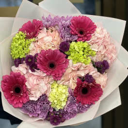 Bouquet of pink gerbera daisies, hydrangeas, and purple chrysanthemums wrapped in white paper