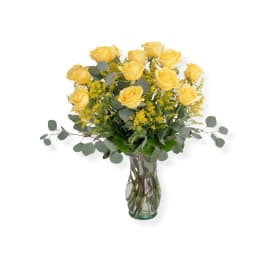 Yellow roses arranged in a clear glass vase with airy filler and eucalyptus
