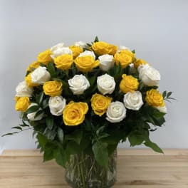 Bouquet of yellow and white roses in a clear glass vase