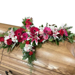 Floral casket spray with red, pink, and white blooms