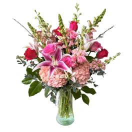 Pink and red roses with lilies and hydrangeas in a glass vase