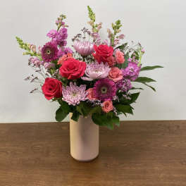 Mixed pink and purple flowers arranged in a white vase