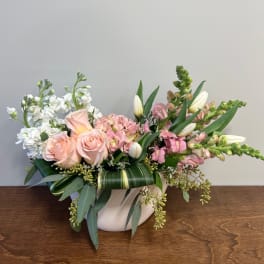 Pink roses and white flowers arranged in a white vase