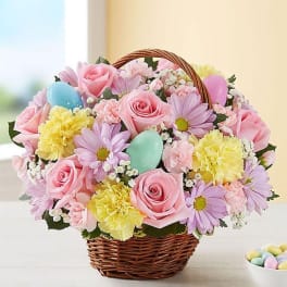 Basket of pink roses, daisies, and yellow carnations with pastel eggs