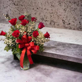 Red roses in a glass vase with a red ribbon bow