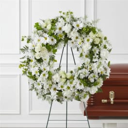 White floral wreath on an easel beside a casket