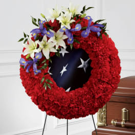 Red floral funeral wreath with white lilies and purple irises on a stand