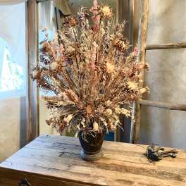Dried wildflower arrangement in a dark vase on a wooden table
