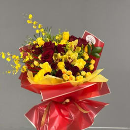 Bouquet of red roses and yellow orchids wrapped in red paper