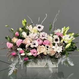 Pink and white floral arrangement in a white box with lilies and roses