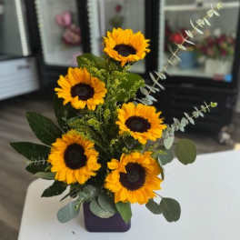 Sunflower arrangement in a purple vase with eucalyptus accents