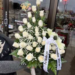 White rose arrangement with lilies and ribbon on a stand