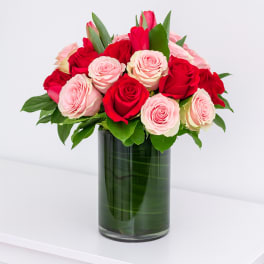 Red and pink roses arranged in a tall glass vase