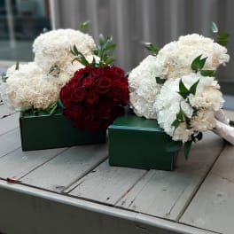Bouquets of white carnations and red roses in green boxes