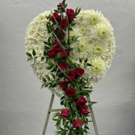 Heart-shaped white floral spray with red roses on an easel