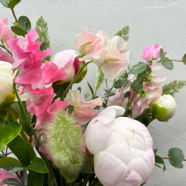 Pink and white flowers arranged with greenery in a bouquet