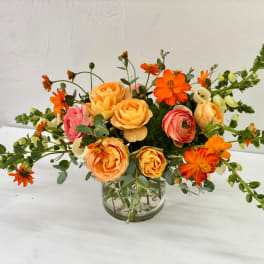 Orange and pink flowers arranged in a clear glass vase