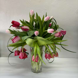 Pink and red tulips arranged in a clear glass vase