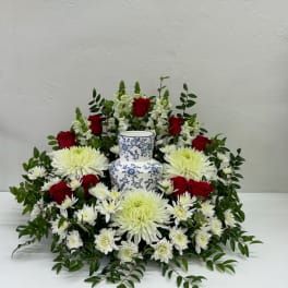Red roses and white chrysanthemums arranged around a blue-and-white vase