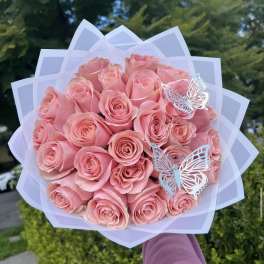 Bouquet of pink roses wrapped in white paper with butterfly decorations