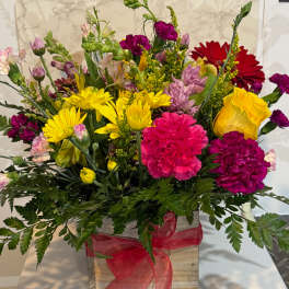 Mixed bouquet in a wooden box with bright yellow, pink, and red flowers