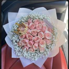 Bouquet of pink roses with white baby's breath in pale wrapping