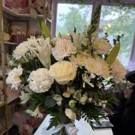 White floral bouquet in a glass vase with a white ribbon