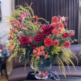 Mixed bouquet of red and pink flowers in a glass compote vase
