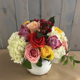 Colorful rose and hydrangea arrangement in a white vase
