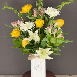 Bouquet of yellow roses, white lilies, and white chrysanthemums in a white vase