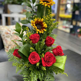 Tall arrangement of red roses and sunflowers with greenery