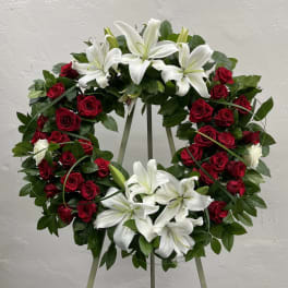 Circular wreath of red roses and white lilies on a stand