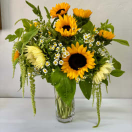 Sunflower bouquet with small white daisies in a clear glass vase