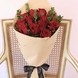 Bouquet of red roses wrapped in tan paper with a black ribbon