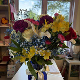 Mixed bouquet of colorful flowers in a blue glass vase with a ribbon