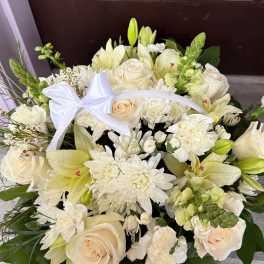 Cream bouquet with roses, lilies, and white blooms tied with a white ribbon