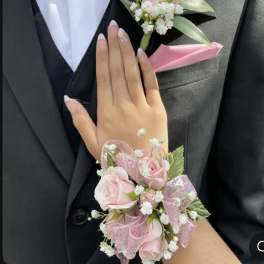 Pink rose boutonniere and wrist corsage on a black suit