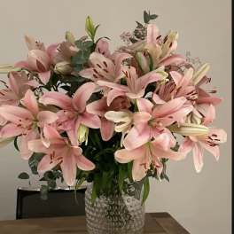 Pink lilies arranged in a clear textured vase