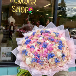 Large bouquet of pink and cream roses with blue filler flowers