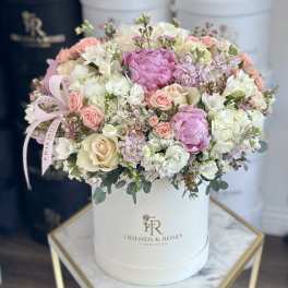 Pink and white roses arranged in a white hat box